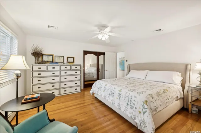 a bedroom with a bed and dresser with wooden floor