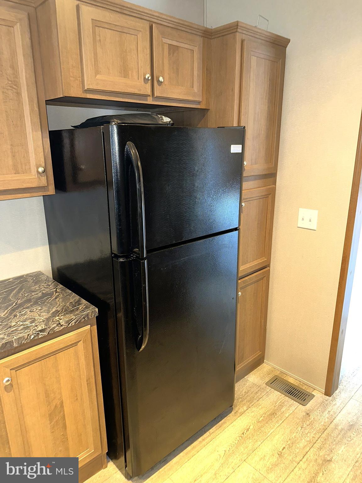 1277 Ritchie Highway, Unit 195 Arnold, MD 21012 - Photo 7 of 30 a kitchen with a refrigerator and cabinets
