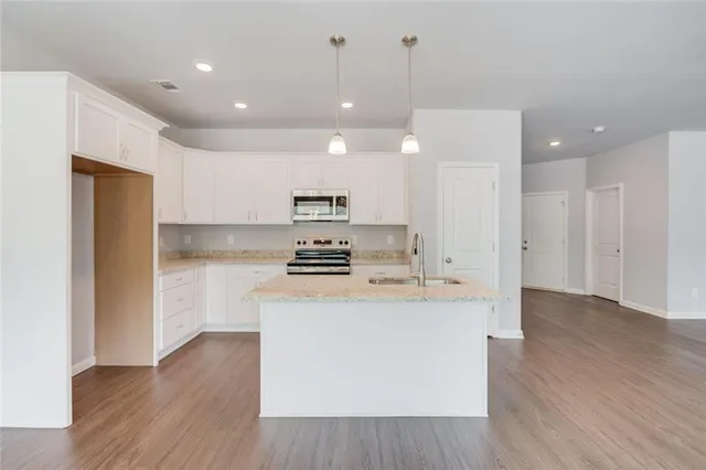 a kitchen with kitchen island a sink a stove a refrigerator and white cabinets