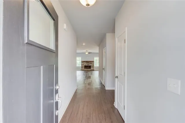a view of a hallway with wooden floor and a bathroom
