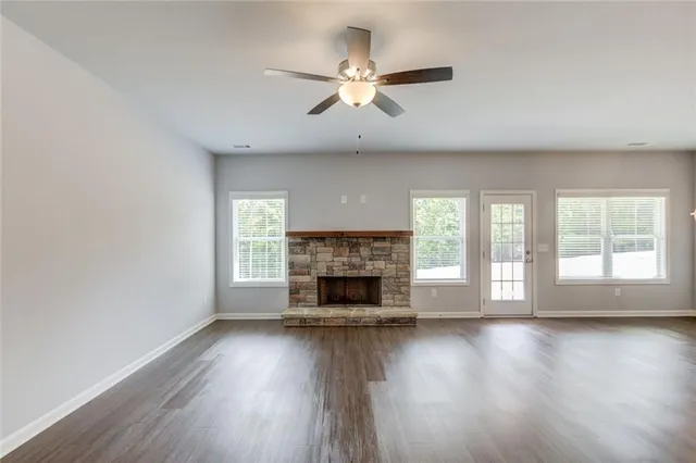 an empty room with wooden floor fireplace and windows