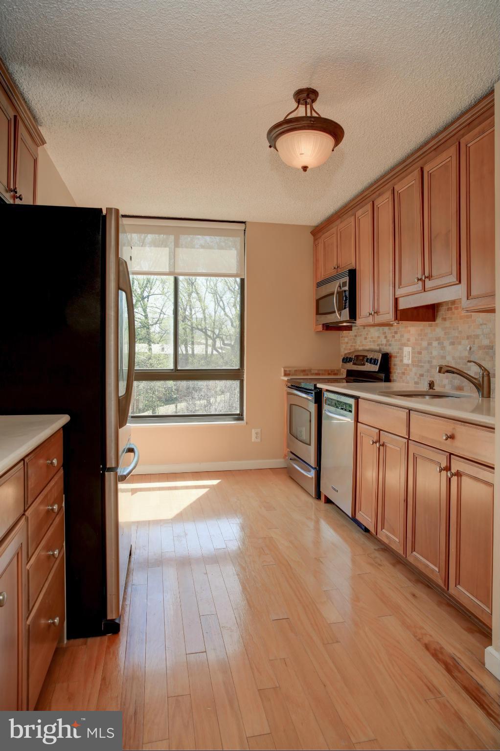 1800 Old Meadow Road, Unit 713 McLean, VA 22102 - Photo 2 of 27 a kitchen with stainless steel appliances granite countertop a stove a sink and a refrigerator with wooden floors