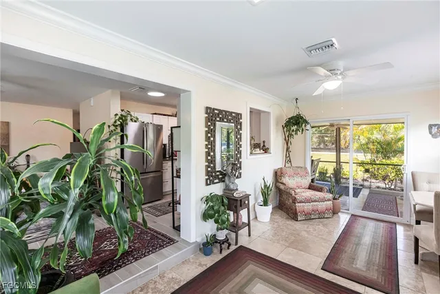 a living room with furniture large windows and plants