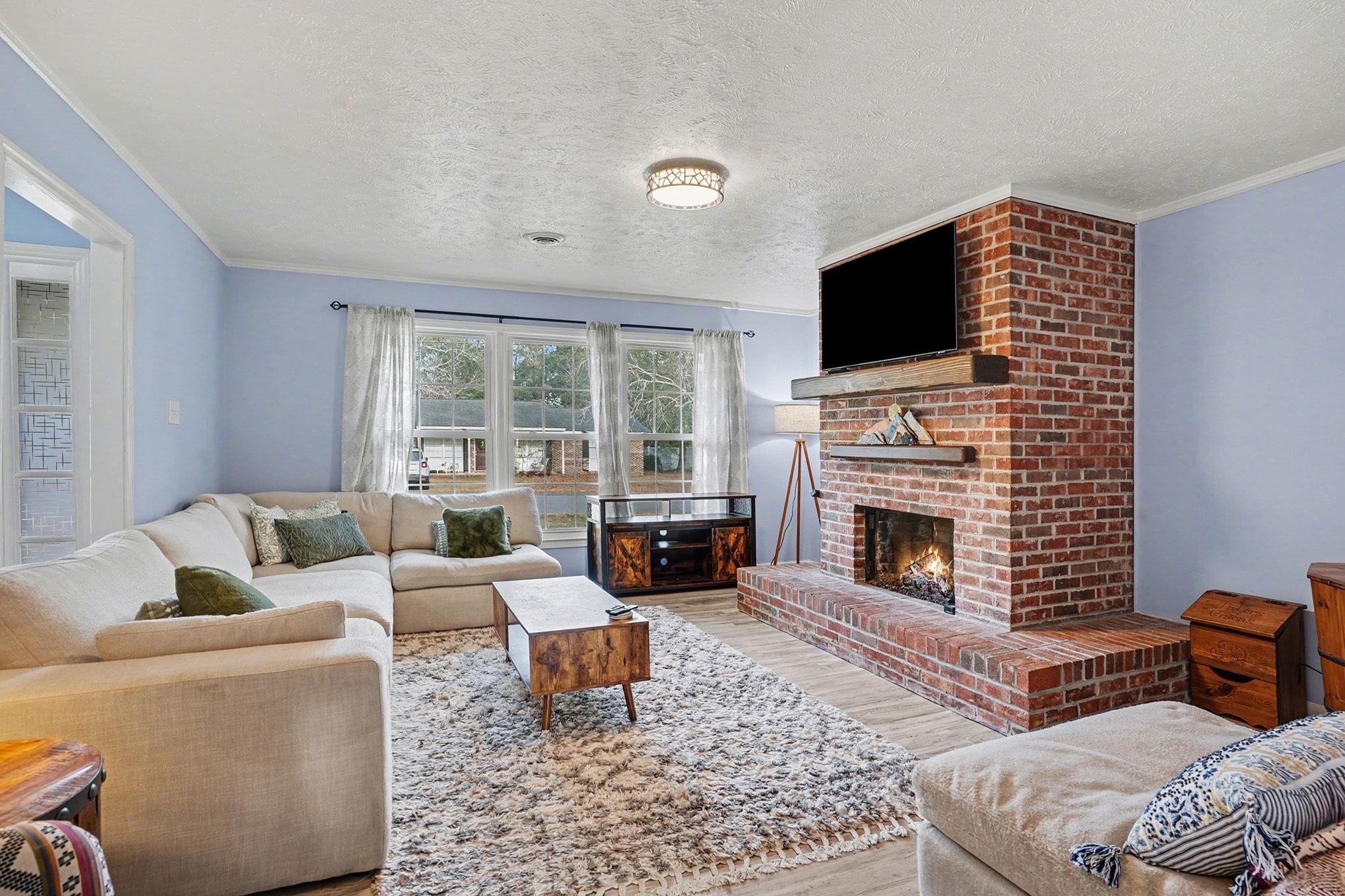 317 Jay Street Murrells Inlet, SC 29576 - Photo 6 of 36 Living area featuring wood finished floors, ornamental molding, a brick fireplace, and a textured ceiling