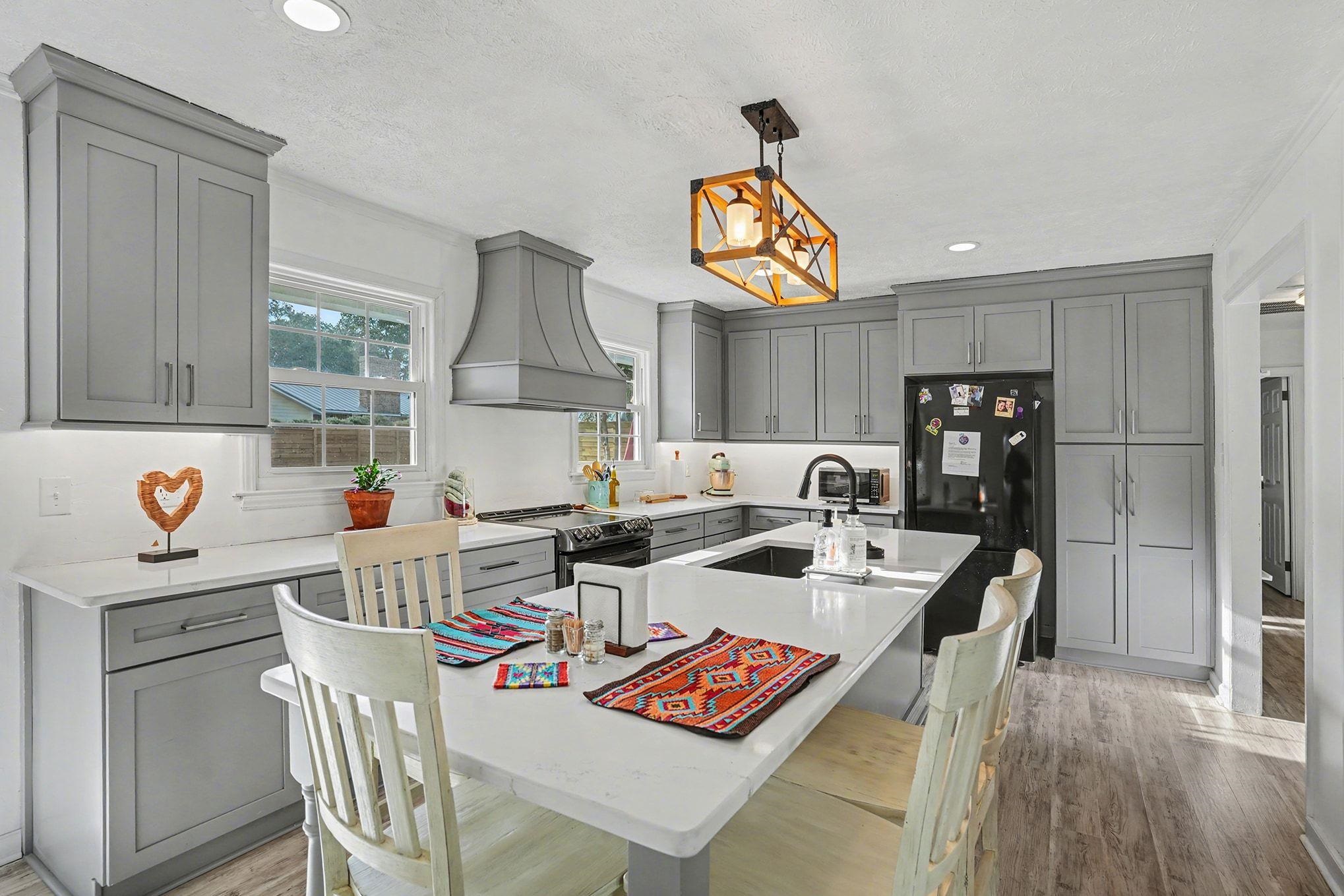 317 Jay Street Murrells Inlet, SC 29576 - Photo 10 of 36 Kitchen featuring gray cabinets, custom exhaust hood, light wood-style flooring, pendant lighting, and a kitchen island with sink