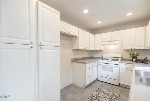 a kitchen with granite countertop white cabinets and white appliances