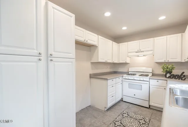 a kitchen with granite countertop white cabinets and white appliances