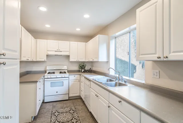 a kitchen with a sink white cabinets and white appliances