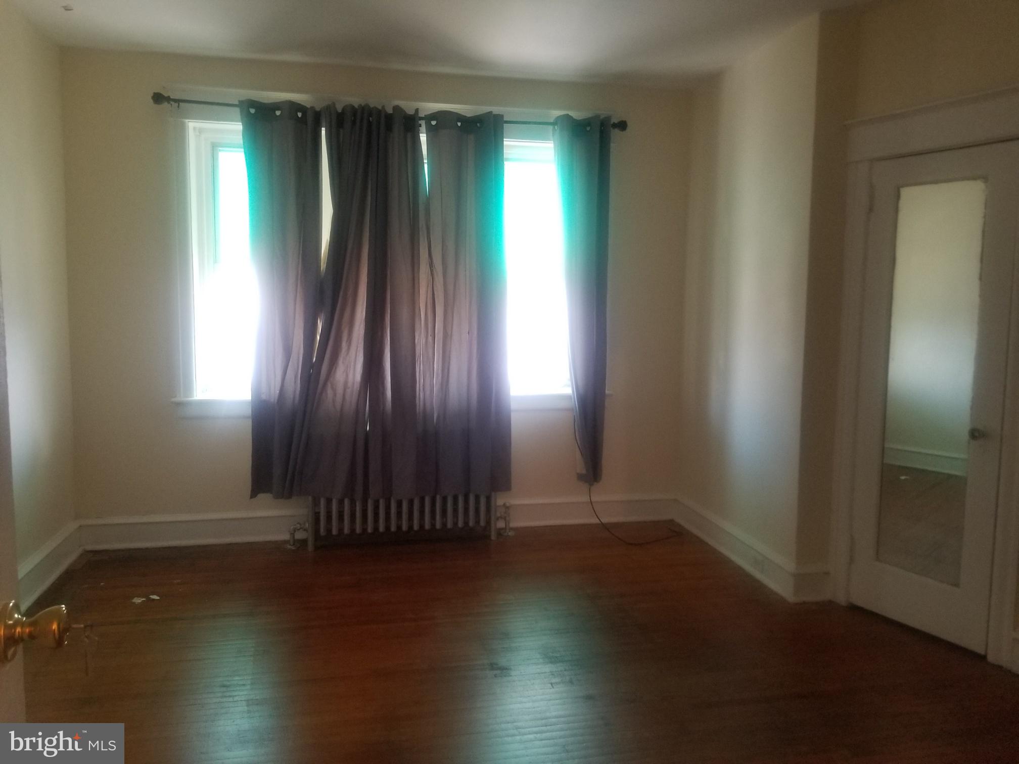 226 Copley Road Upper Darby, PA 19082 - Photo 9 of 10 an empty room with wooden floor and windows with curtains