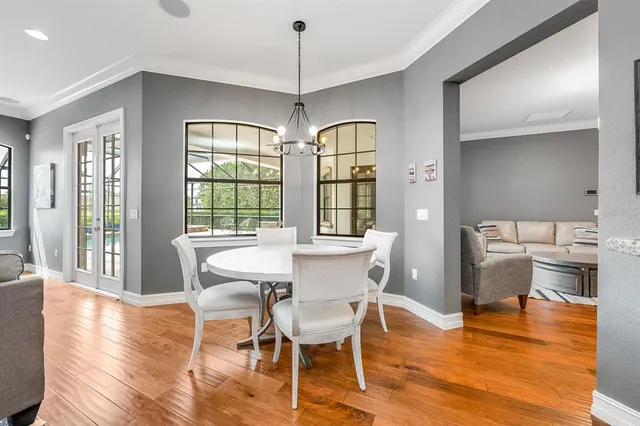 a dining room with wooden floor a chandelier a glass table and chairs