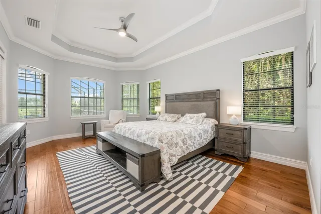 a bedroom with a large bed a chandelier and windows