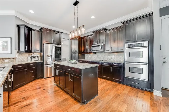 a kitchen with stainless steel appliances granite countertop a stove a refrigerator and a sink