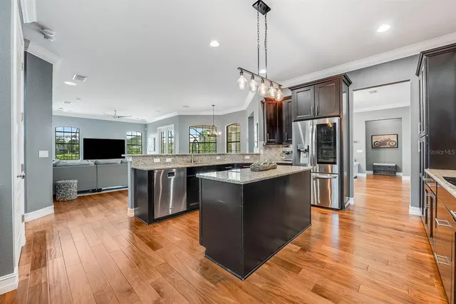a large kitchen with stainless steel appliances kitchen island granite countertop a large counter top and wooden floors