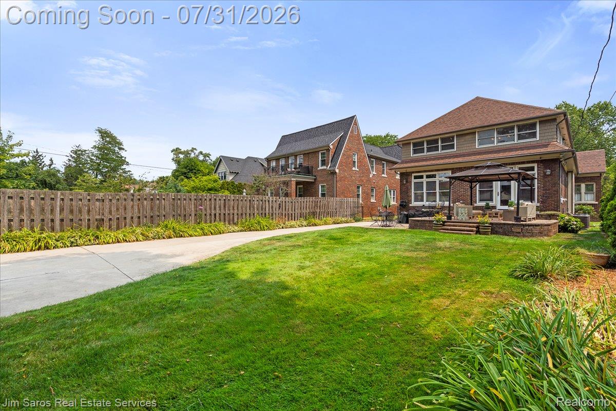 Spacious backyard featuring a manicured lawn, paved pathway, and a privacy fence
