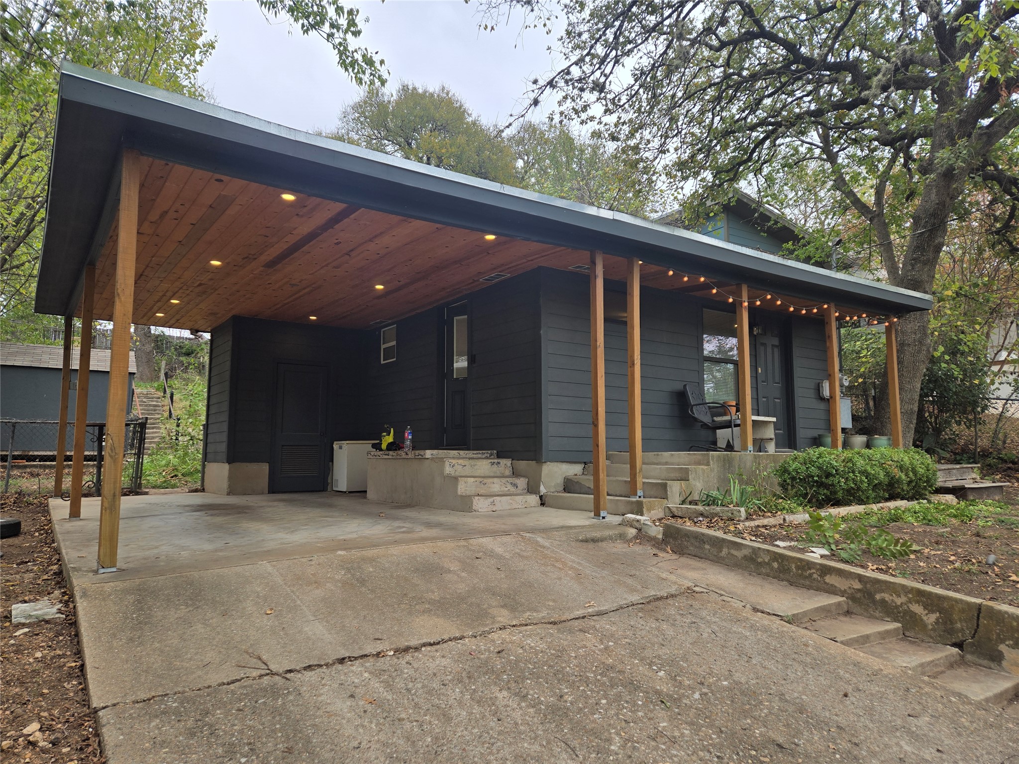 View of front of home with concrete driveway, a carport, and a porch