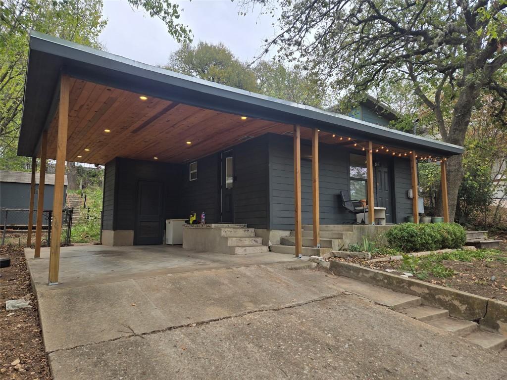 View of front of home with concrete driveway, a carport, and a porch