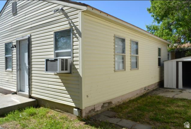 230 North 2nd Street Tooele, UT 84074 - Photo 17 of 18 Exterior featuring horizontal siding, multiple windows, an exterior door, and a metal storage shed