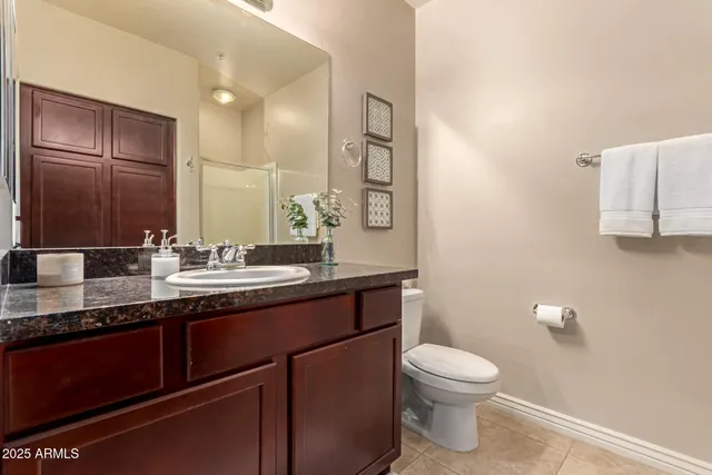 a bathroom with a granite countertop toilet sink and mirror