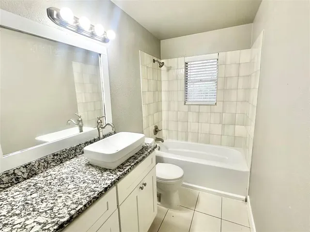 a bathroom with a granite countertop sink a toilet a mirror and bathtub