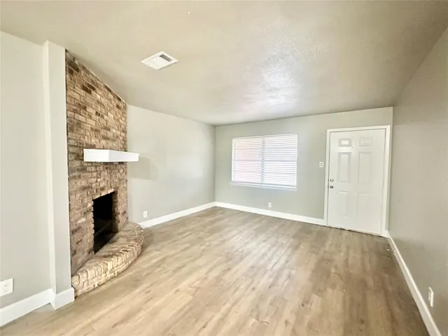 a view of empty room with wooden floor and fireplace