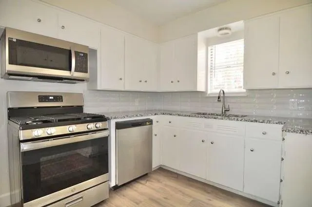 a kitchen with granite countertop a stove top oven microwave and cabinets