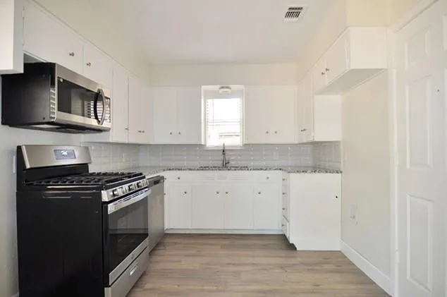 a kitchen with stainless steel appliances granite countertop a stove a sink and a microwave