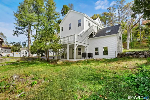 a view of a white house next to a yard with big trees