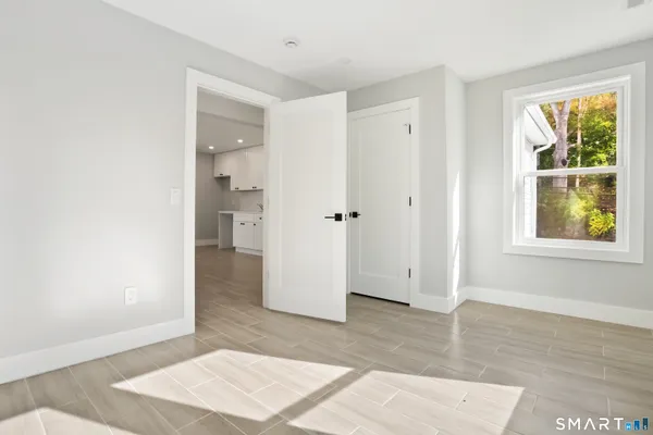 a view of an empty room with window and wooden floor