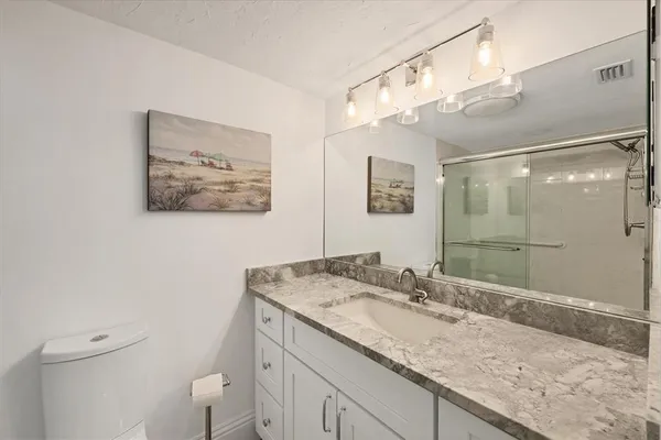 a bathroom with a granite countertop sink a mirror and a shower