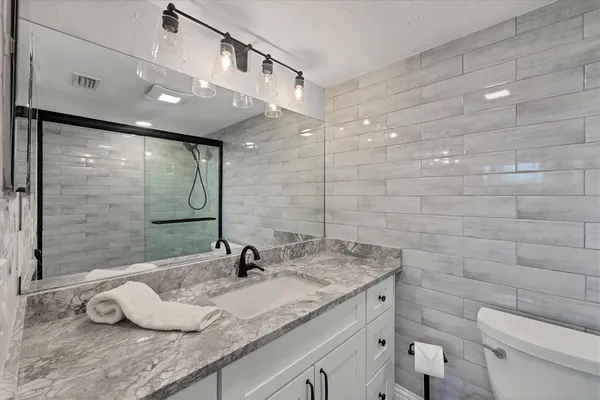 a bathroom with a granite countertop sink a toilet and a shower