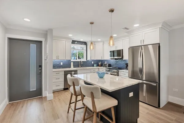 a kitchen with refrigerator a sink and chairs