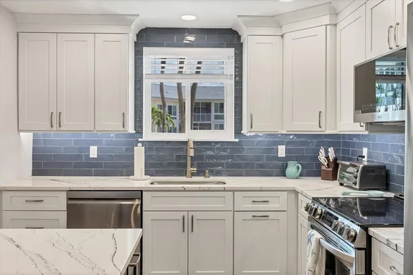 a kitchen with stainless steel appliances white cabinets and a stove top oven