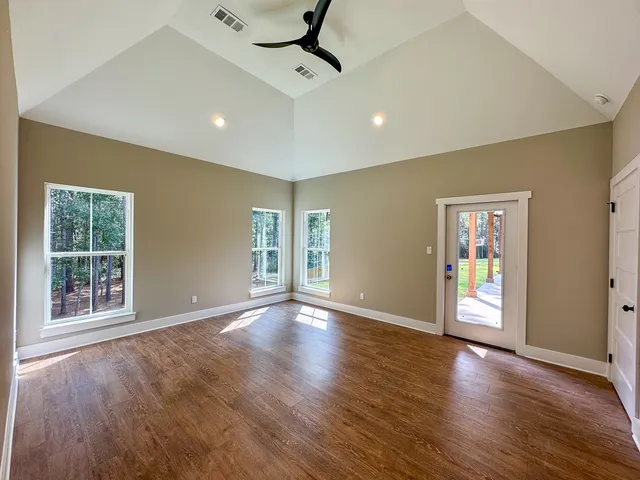 a view of an empty room with glass door and wooden floor