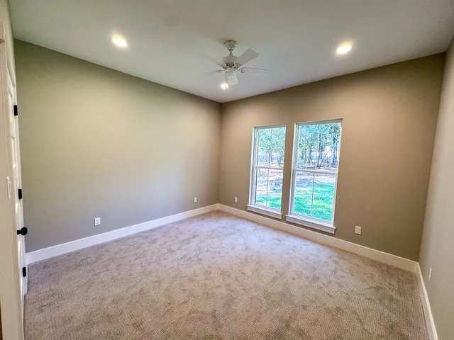 an empty room with windows and ceiling fan