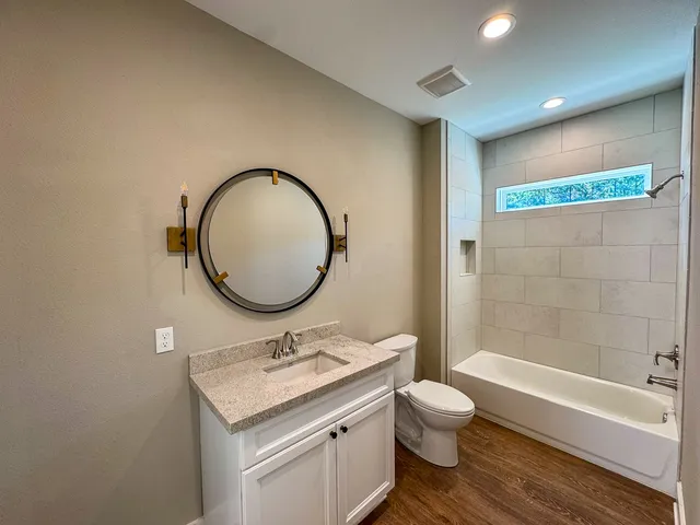 a bathroom with a granite countertop sink toilet a mirror and bathtub