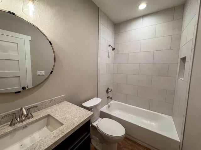 a bathroom with a granite countertop sink a toilet and shower