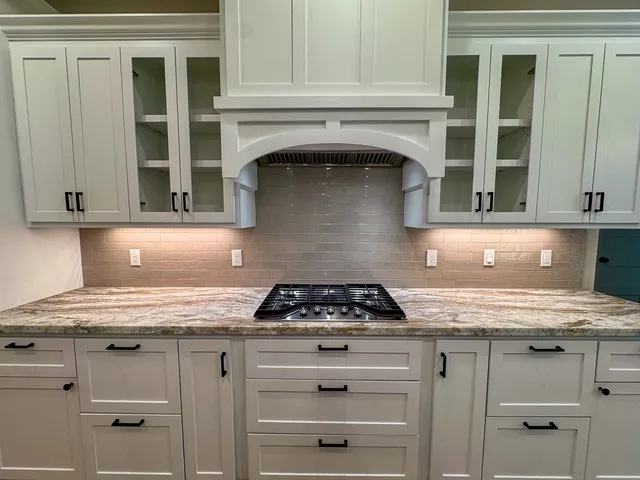 a kitchen with granite countertop white cabinets and appliances