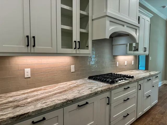a kitchen with granite countertop stainless steel appliances sink stove and cabinets