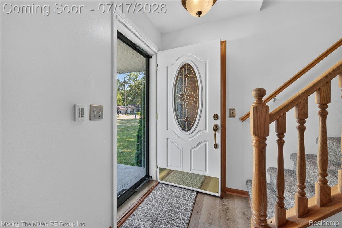40162 Alden Road Belleville, MI 48111 - Photo 6 of 67 Entryway with a white paneled door featuring an oval decorative glass insert, wood-finish flooring, and a carpeted staircase with wood banisters