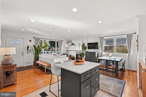a living room with stainless steel appliances kitchen island granite countertop wooden floor a dining table and chairs