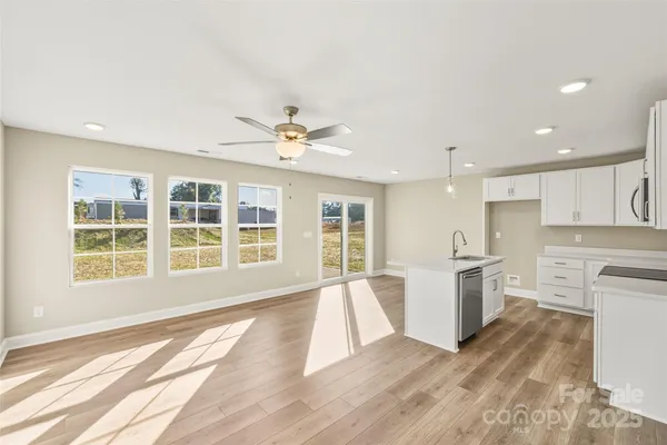 a view of an empty room with a window and kitchen view