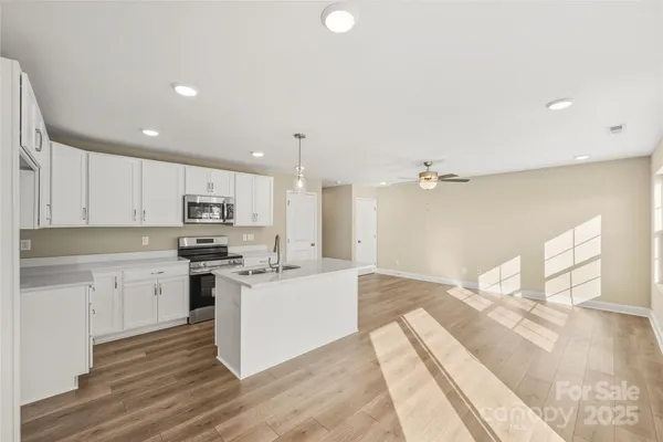 a large white kitchen with cabinets appliances and a wooden floor