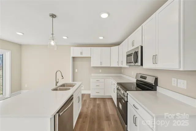 a kitchen that has a lot of white cabinets and stainless steel appliances