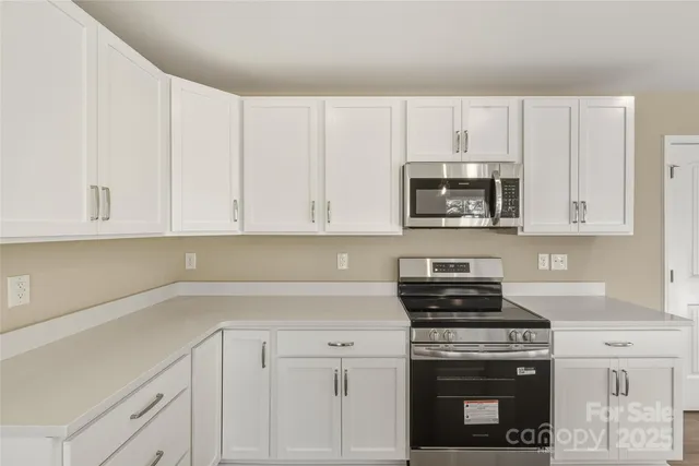 a kitchen with white cabinets and stainless steel appliances
