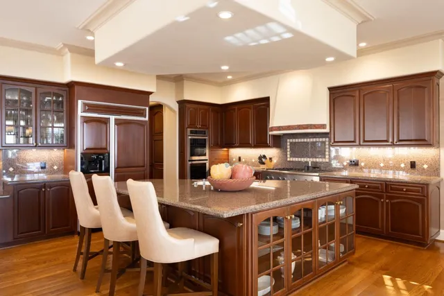 a kitchen with stainless steel appliances granite countertop a table chairs sink refrigerator and cabinets