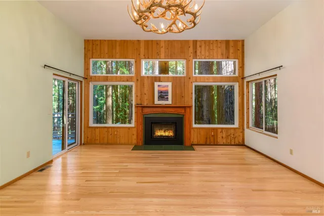 a view of an empty room with glass door and wooden floor
