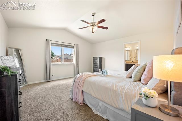 7148 Red Cardinal Loop Colorado Springs, CO 80908 - Photo 25 of 50 Bedroom with light colored carpet, lofted ceiling, baseboards, ensuite bathroom, and ceiling fan