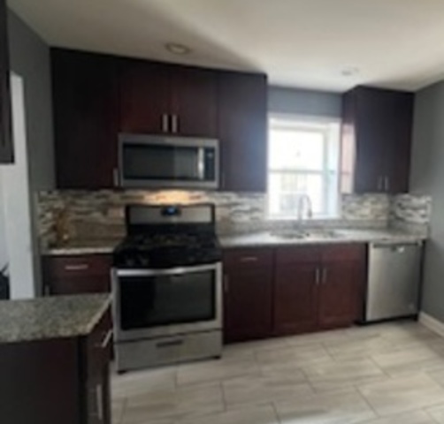 14918 Evers Street Dolton, IL 60419 - Photo 17 of 29 a kitchen with granite countertop a stove top oven microwave and cabinets