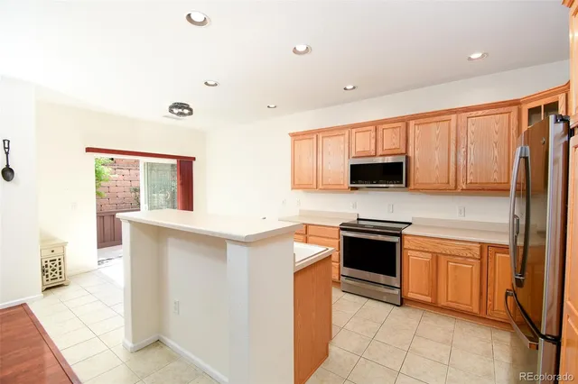 a kitchen with stainless steel appliances granite countertop a stove top oven a sink a refrigerator and white cabinets with wooden floor