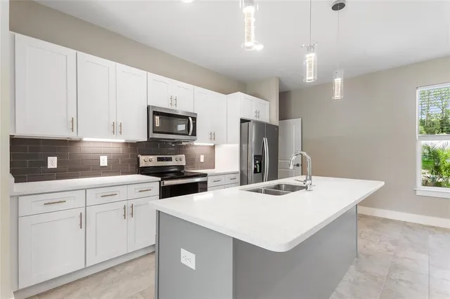 a large kitchen with kitchen island a refrigerator a sink stainless steel appliances and cabinets